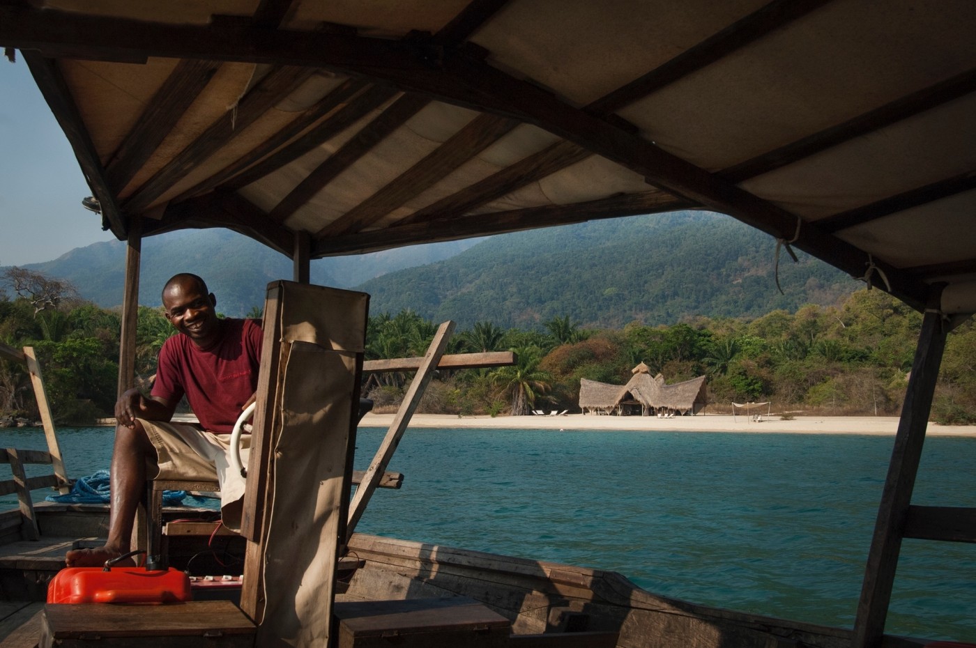 Smiling man on a boat with Greystoke Mahale, Tanzania in the background