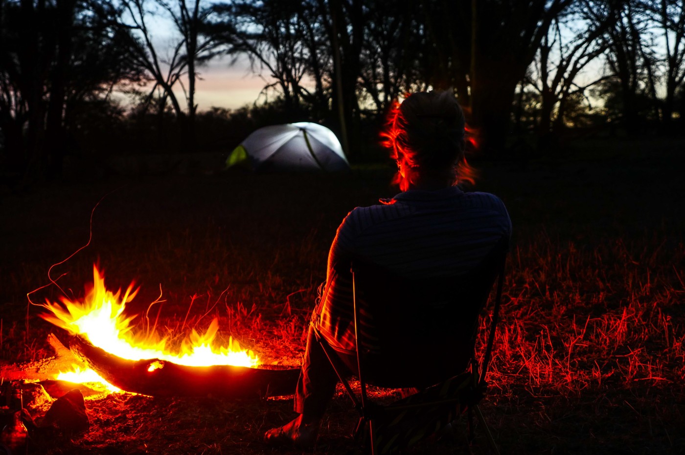 person in front of bonfire and tent in the background at Wayo Walking Fly Camp, Serengeti, Tanzania
