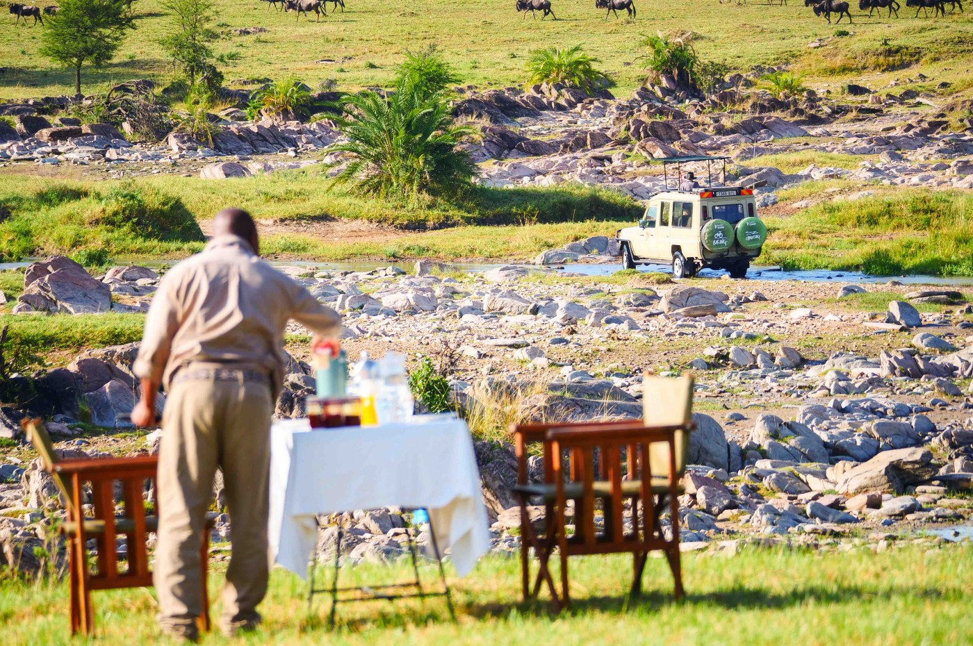 table and chair ready with lunch and waiter at Wayo Serengeti Green Camp, Tanzania