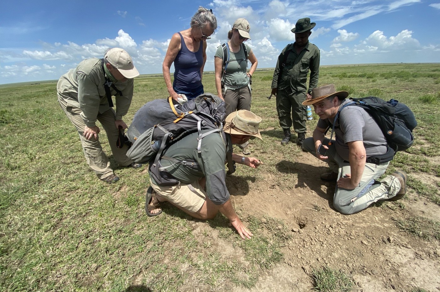 People looking at animal footprints at Wayo Walking Safari Camp, Serengeti, Tanzania